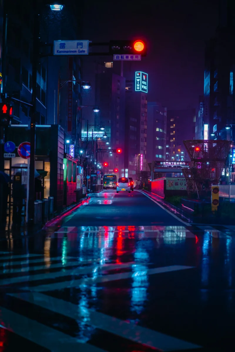 A high-resolution 4K AMOLED wallpaper of a wet street in Tokyo at night, glowing with vivid neon lights and cyberpunk aesthetic reflections.