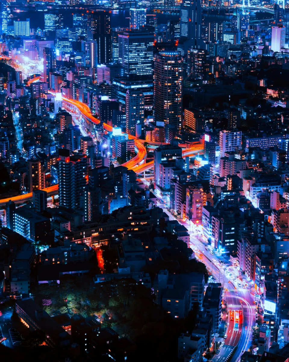 Tokyo night city timelapse photography showing vibrant vehicle light trails and towering illuminated buildings for 4K mobile AMOLED wallpaper